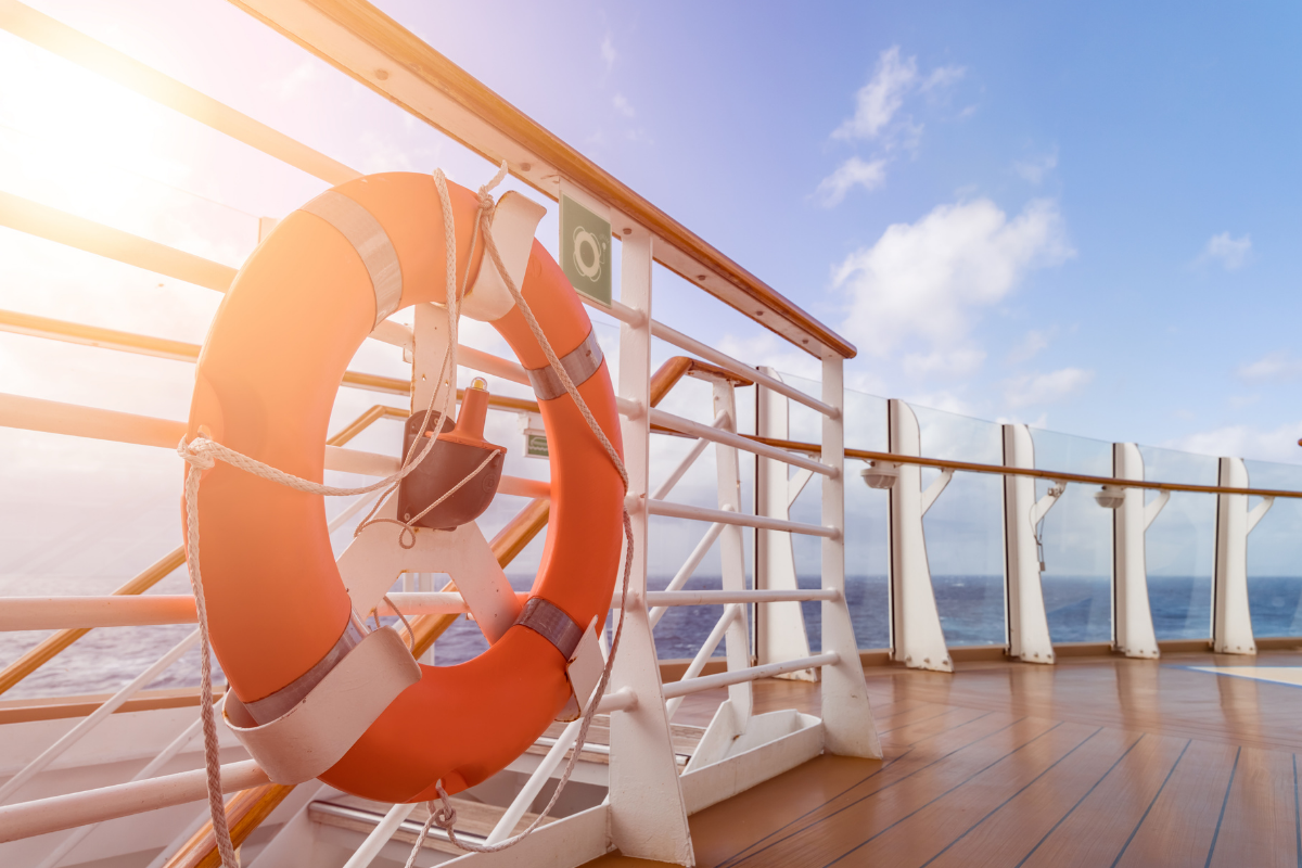 A large orange lifeboat on the side of a cruise ship, representing cruise safety secrets.